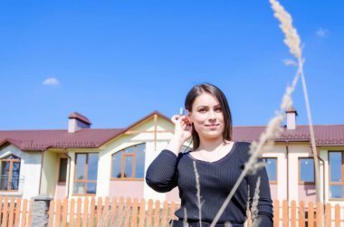 Güzel genç kız portre yeni bir yazlık ev arka plan üzerinde.