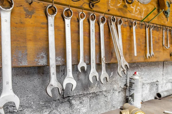 Gamla skiftnycklar hänga över bordet i verkstaden — Stockfoto