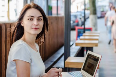 Üzerinde çalıştığı bir sokak kafede bir masada oturan güzel kız bir 
