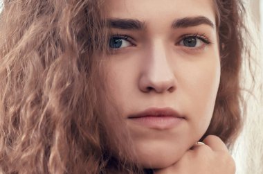 Güzel kıvırcık bir kızın güneşli portresi, kameraya bak.