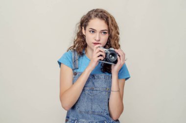 Kot pantolon giymiş kıvırcık esmer, elinde film kamerasıyla sette eğleniyor..