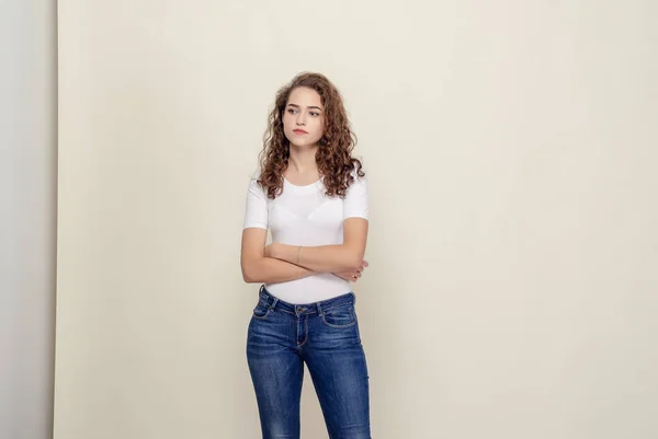 Retrato menina de cabelos encaracolados em T-shirt branca e jeans na luz — Fotografia de Stock