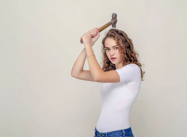 Bella ragazza tiene un martello in mano, oscilla per colpire — Foto Stock