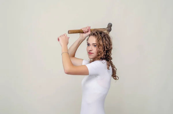Bella ragazza tiene un martello in mano, oscilla per colpire — Foto Stock