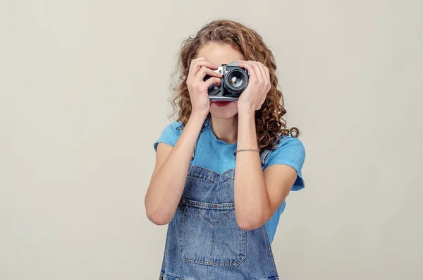 Riccio bruna ragazza in denim tuta è in possesso di un vintage fotocamera — Foto Stock