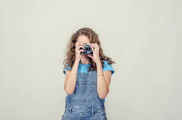 Riccio bruna ragazza in denim tuta è in possesso di un vintage film — Foto Stock