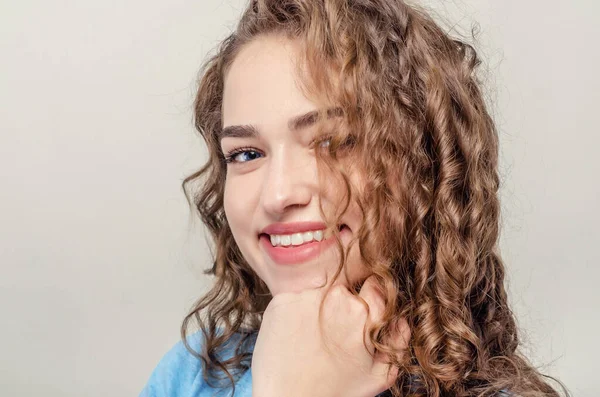 Retrato de menina bonita, close-up. Cabelo encaracolado. A brincar aos cabelos. Sorriso sedutor — Fotografia de Stock