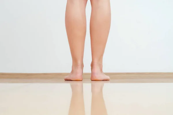 Le gambe femminili camminano su un pavimento caldo di piastrelle giallo chiaro — Foto Stock