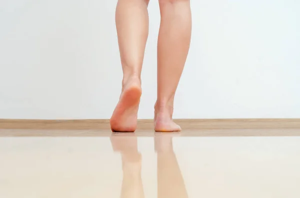 Жіночі ноги ходять на теплій підлозі світло-жовтих плиток — стокове фото