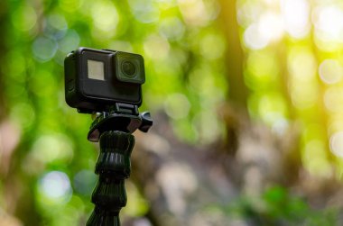 Yeşil orman arka planında esnek bir üçayak üzerinde aksiyon kamerası