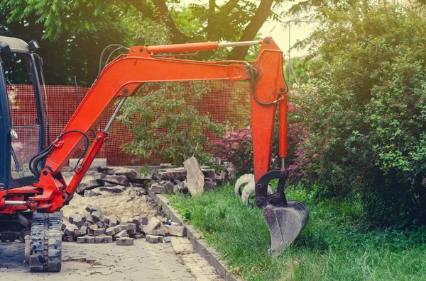 芝生の近くの歩道上の小さな掘削機。都市部での修理 — ストック写真