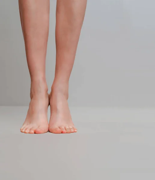 Schlanke weibliche Beine auf Zehen auf hellgrauem Hintergrund — Stockfoto