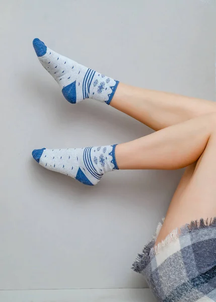 Λεπτά πόδια μιας γυναίκας με κάλτσες λυγισμένες στα γόνατά της σε γκρι φόντο. — Φωτογραφία Αρχείου