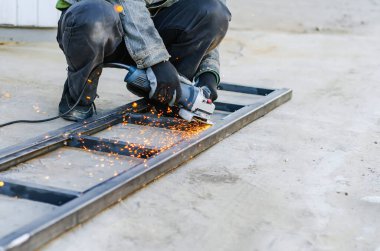 Adam elleri elektrikli testere ile metali kesiyor.