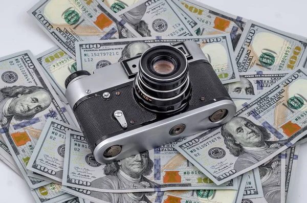 Vintage film camera on scattered American dollars. Concept of earning on photo stocks.