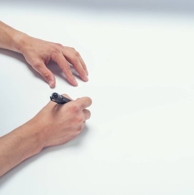 Erkek el beyaz kağıda siyah kalem yazar.