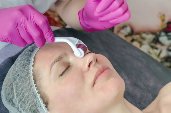 Close-up portrait of woman processing skin in beauty salon. Doctor prepares skin using a mesoscooter.