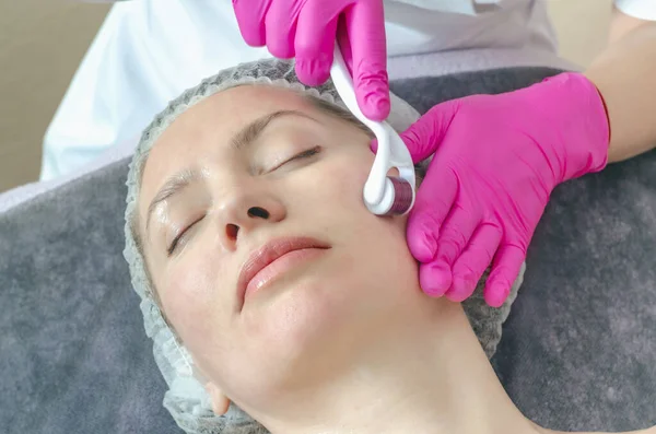 Close-up portrait of woman processing skin in  beauty salon. Doctor prepares skin using a mesoscooter.