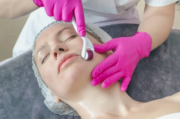 Close-up portrait of woman processing skin in  beauty salon. Doctor prepares skin using a mesoscooter.