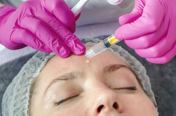 美容師は若返りの手順のために患者の顔にヒアルロン酸を適用します — ストック写真