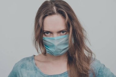 Tıbbi maske takan bir kadının portresi kameraya bakıyor, izole edilmiş. Grip salgını, toz alerjisi, virüs koruması. Covid-19, koronavirüs salgını