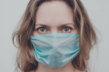 Tıbbi maske takan bir kadının portresi kameraya bakıyor, izole edilmiş. Grip salgını, toz alerjisi, virüs koruması. Covid-19, koronavirüs salgını