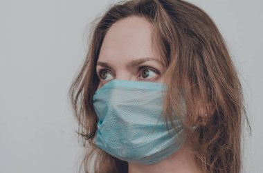 Tıbbi maske takan bir kadının portresi kameraya bakıyor, izole edilmiş. Grip salgını, toz alerjisi, virüs koruması. Covid-19, koronavirüs salgını