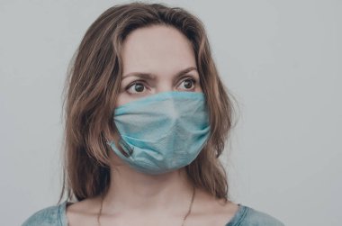 Tıbbi maske takan bir kadının portresi kameraya bakıyor, izole edilmiş. Grip salgını, toz alerjisi, virüs koruması. Covid-19, koronavirüs salgını