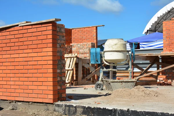 Mezclador de concreto de cemento en el sitio de construcción de la casa. Mezclador de hormigón, La mezcladora de hormigón es un dispositivo que combina homogéneamente cemento, agregado como arena o grava, y agua para formar hormigón . —  Fotos de Stock