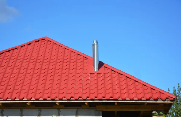 New red metal tiled roof with steel chimney house roofing construction exterior without rain gutter system. — Stock Photo, Image