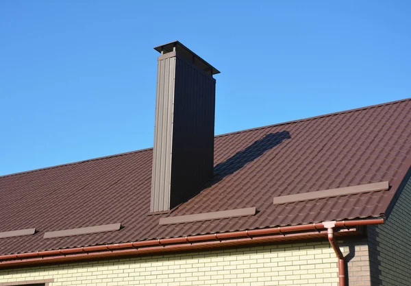 New brown metal tiled roof with plastic rain gutter system chimney house roofing construction exterior. — Stock Photo, Image