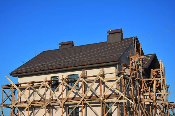 Schilderen en pleisteren van buitenkant huis steigers Facade muur met nieuwe metalen dakpannen buiten. — Stockfoto