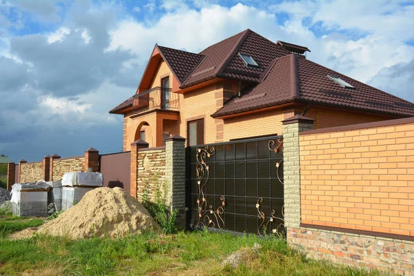 Clôture en brique et en métal avec porte en métal de style moderne Design décoratif Mur en brique fissurée avec construction de maison neuve Extérieur. Idées de conception de maison de barrière en acier . — Photo