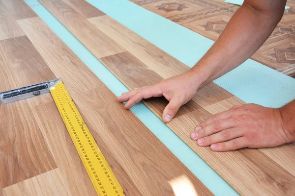 Uomo posa pavimenti in laminato. Installazione di pavimenti in laminato di legno. Passo dopo passo . — Foto Stock