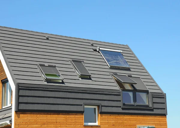 太陽電池パネルおよびエネルギー効率の天窓とドーマ屋外モダンな家の屋根に太陽熱温水. — ストック写真