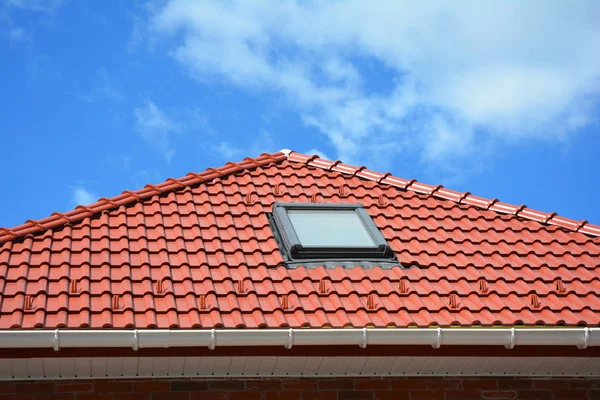 Dakraam op rode keramische tegels huis dak met regengoot. Dakramen, dakvensters en zon Tunnels. Attic dakraam oplossing buiten. — Stockfoto