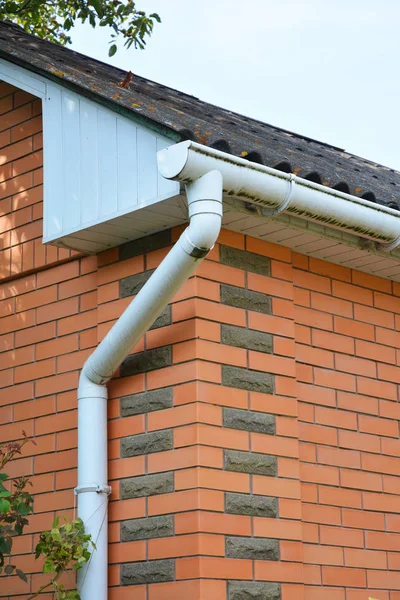 レンガの家雨溝屋外パイプラインのビューを閉じます 家の雨樋 プラスチック雨樋システム樋 排水パイプの外観 — ストック写真