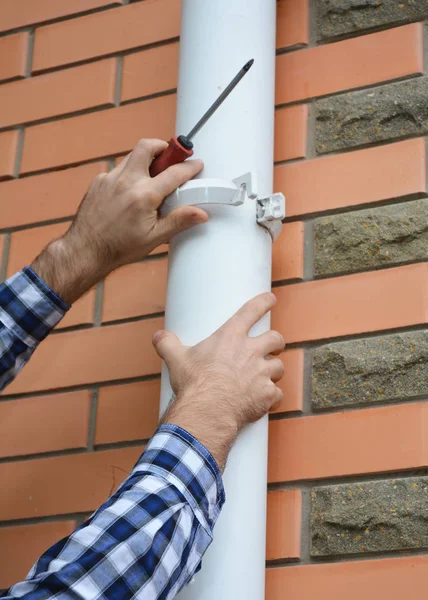 Aannemer installeren en reparatie pvc regen goot systeem pijpleiding. Guttering, kunststof dakgoten, & Drainage door Handyman handen. — Stockfoto