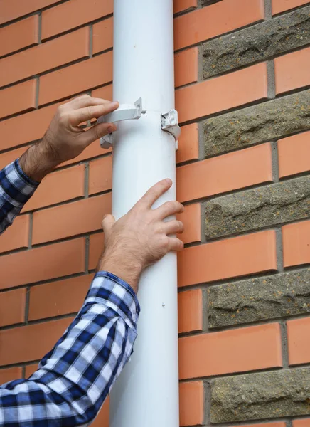 Aannemer installeren en reparatie pvc regen goot systeem pijpleiding houder. Kunststof Guttering, & Drainage door Handyman handen. — Stockfoto