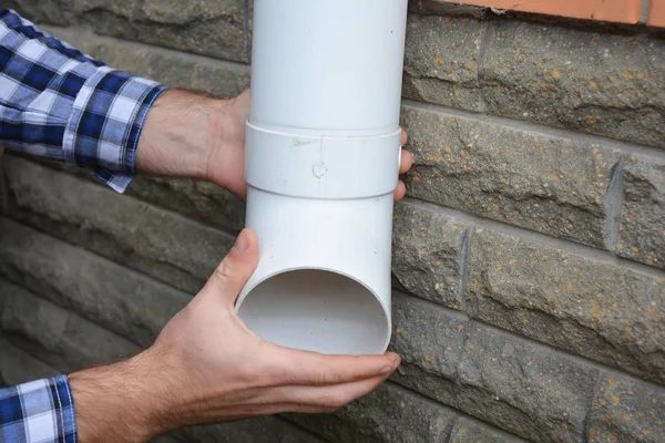 Adam plastik yağmur oluk sistemi boru hattı yükleme. Guttering, oluklar, plastik Guttering, Guttering ve drenaj el ulağı eller tarafından. Boru bağlantı parçaları guttering aşağı. DIY.