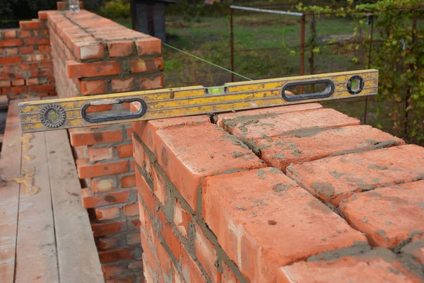 Briquetage avec niveau d'esprit pour vérifier le nouveau mur de la maison en brique rouge en plein air. Briquetage de base sur le chantier de construction de la maison — Photo