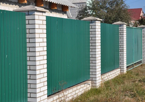 绿色金属门栅栏与白色砖。钢板围栏. — 图库照片