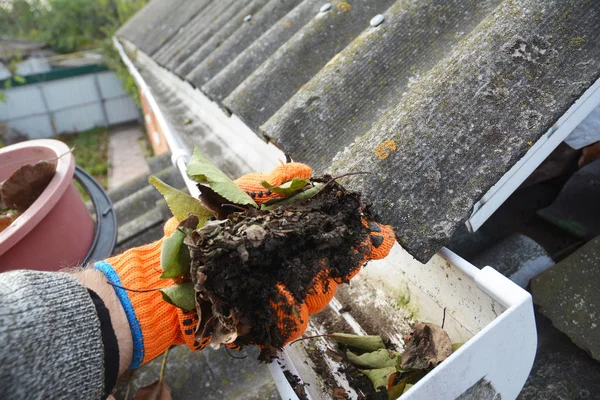 Regen goot schoonmaken. Scooping bladeren uit de goot. Schoon en reparatie regen dakgoten en regenpijp met dakdekker handen. Stap voor stap. — Stockfoto