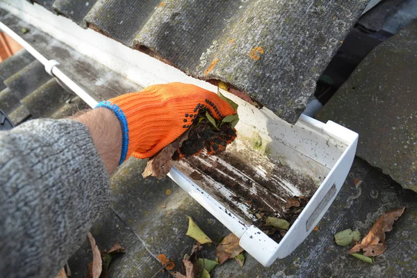 Limpieza de canalones de lluvia de hojas en otoño con la mano. Consejos de limpieza de canaletas de techo. Limpia tus canaletas antes de que limpien tu billetera. Paso a paso. Limpieza de canalones . —  Fotos de Stock