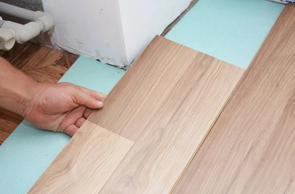 Man Installing New Laminate Wood Flooring in Problem Area.