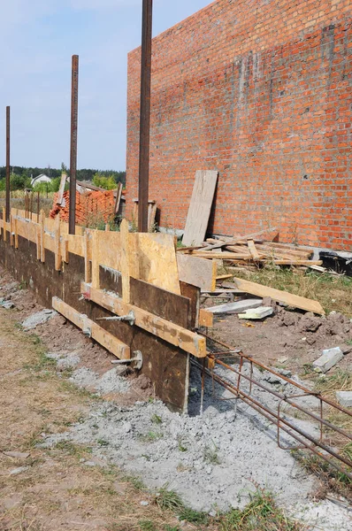 Construcción de cimientos de valla. Barras de acero de barras de refuerzo, barras de hormigón de refuerzo con varilla de alambre y encofrado de madera para cimentación de valla . —  Fotos de Stock