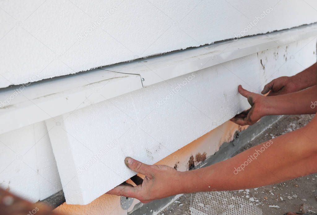 Contractor insulating foundation with hands and polystyrene foam boards for House Energy Saving. Foundation Insulation.