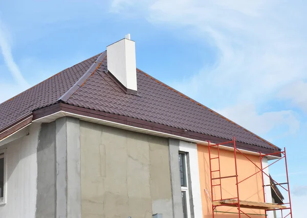 Painting,Plastering, Stucco Exterior House Wall. Facade Thermal Insulation and Painting Repair Works During Exterior Renovations. House Roofing Construction, Soffits and Roof Insulation Repair.