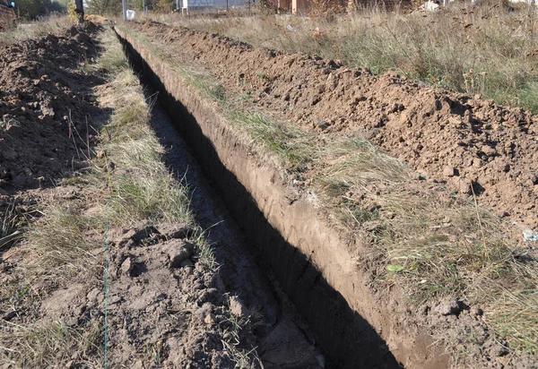 Earthworks, digging trench. Long earthen trench dug to lay pipe or optic fiber. Digging a trench. — Stock Photo, Image