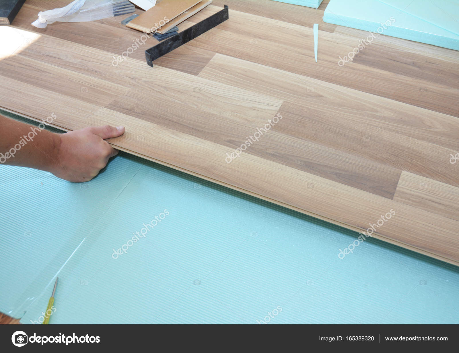 Contractor Installing Wooden Laminate Flooring With Insulation And Contractor Installing Wooden Laminate Flooring With Insulation And Soundproofing Sheets Man Laying